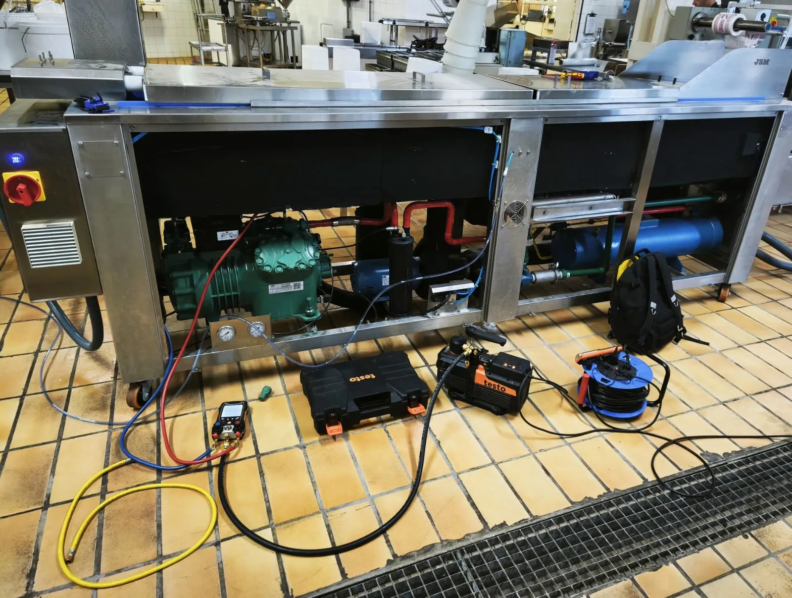 Manómetro digital y bomba de vacío conectados a un equipo frigorífico en una planta de producción alimentaria