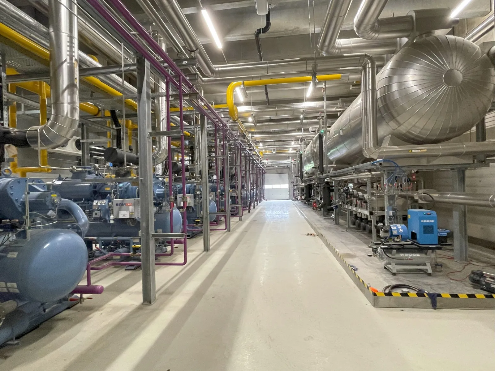 Sala de máquinas de una instalación frigorífica industrial con compresores, tuberías aisladas y recipientes